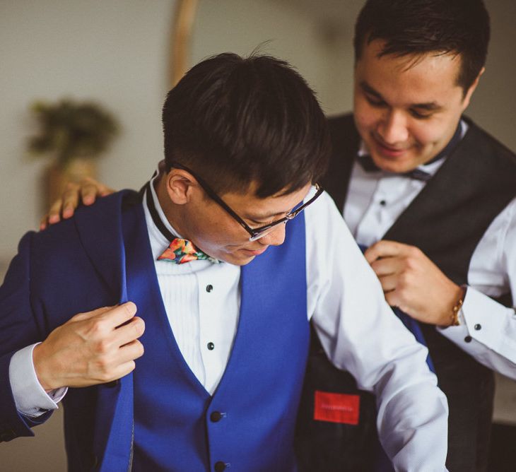 Groom on the wedding morning putting on his blue jacket 