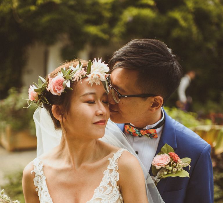 Groom kissing his bride in a blush pink and coral flower crown with matching bouquet 