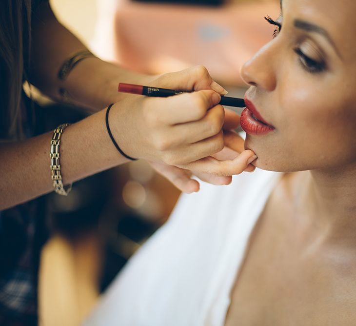 Black bride on her wedding morning having her makeup down with red lipstick and winged eyeliner | Lelia Scarfiotti Photography