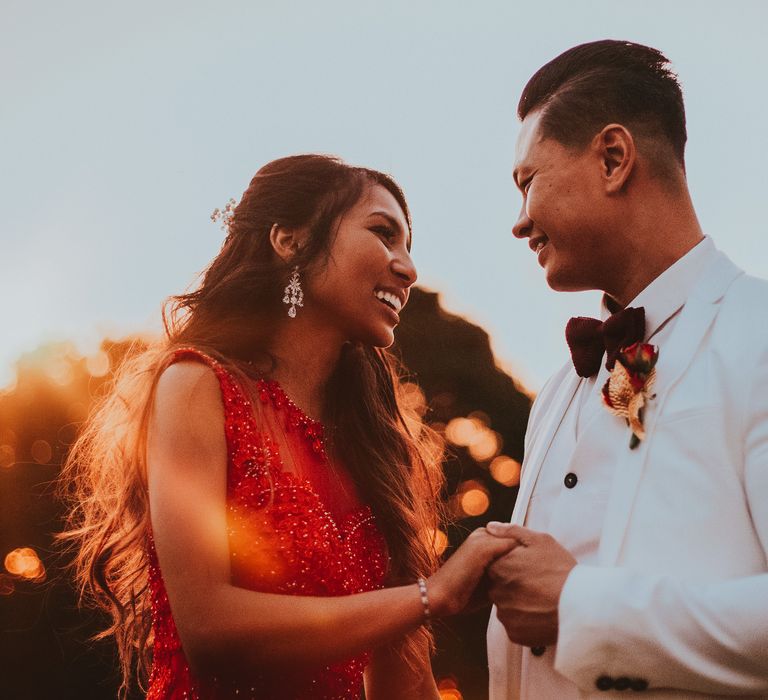 Bride & groom laugh outdoors and hold hands