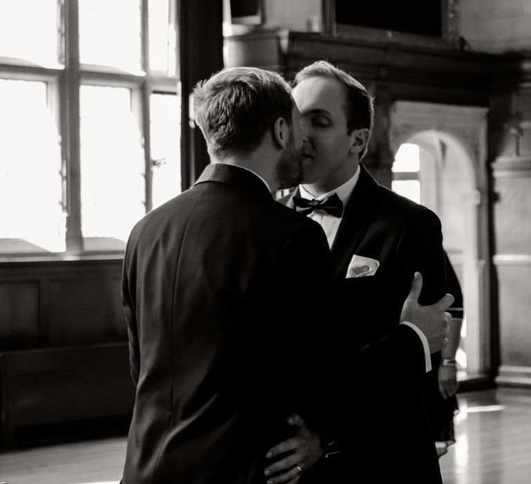 Black & white image of grooms kissing on wedding day