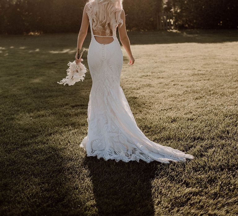 Golden hour portrait by Emmy Shoots with bride in a fitted wedding dress with puddle train and low back detail 