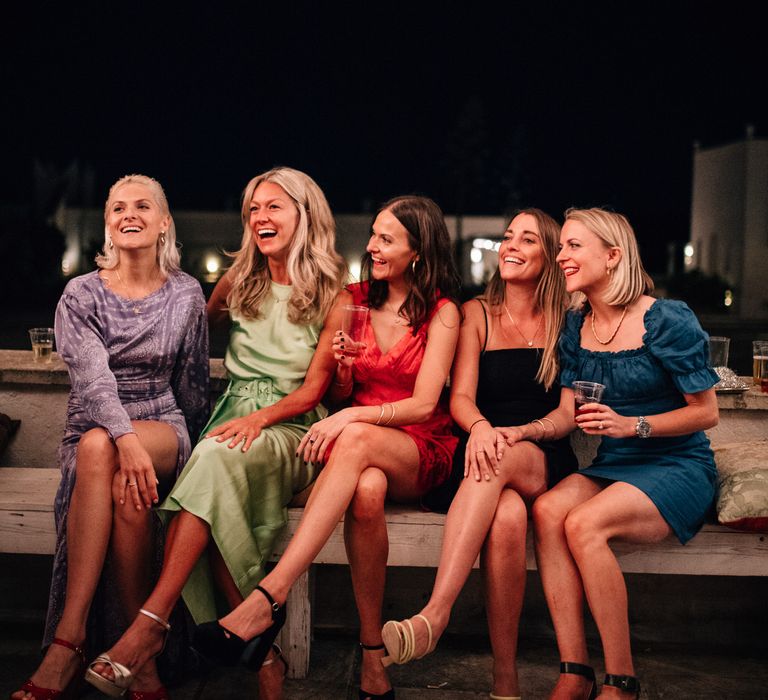 The bride and her bridesmaids in bright coloured dresses the evening before her wedding