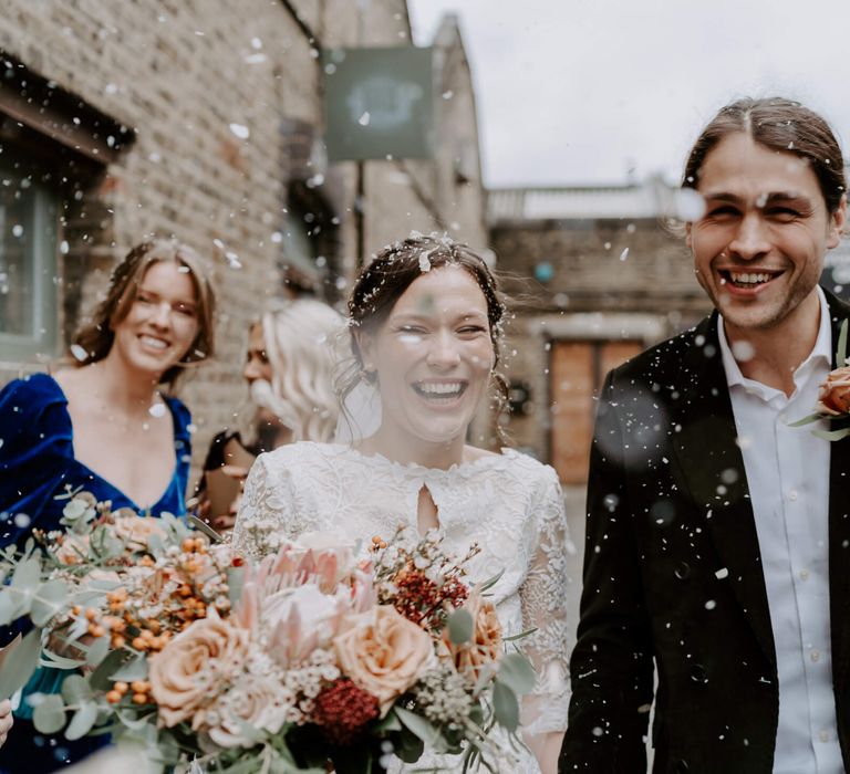 Bride and groom confetti moment with peach rose wedding bouquet