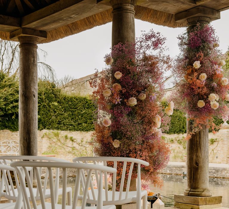 White chairs line aisle as floral decor creeps up pillars