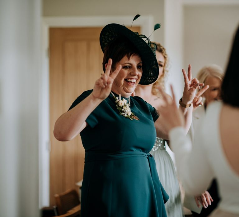 Mother of the bride in a deep green dress and matching hat on the wedding morning 