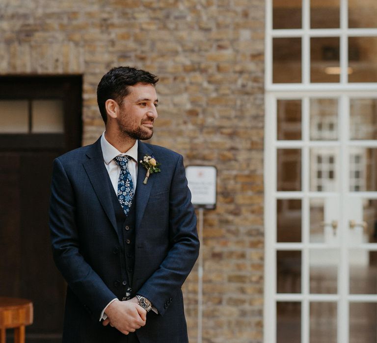 Groom wearing navy blue Ted Baker suit with floral tie