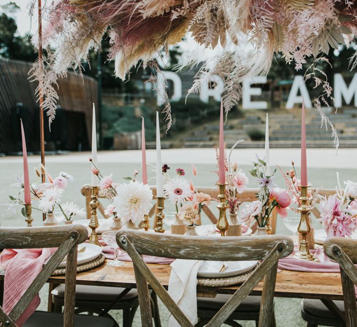 Pastel pink wedding table decor with taper candles, flowers in ink wedding and a pampas grass installation overhead 