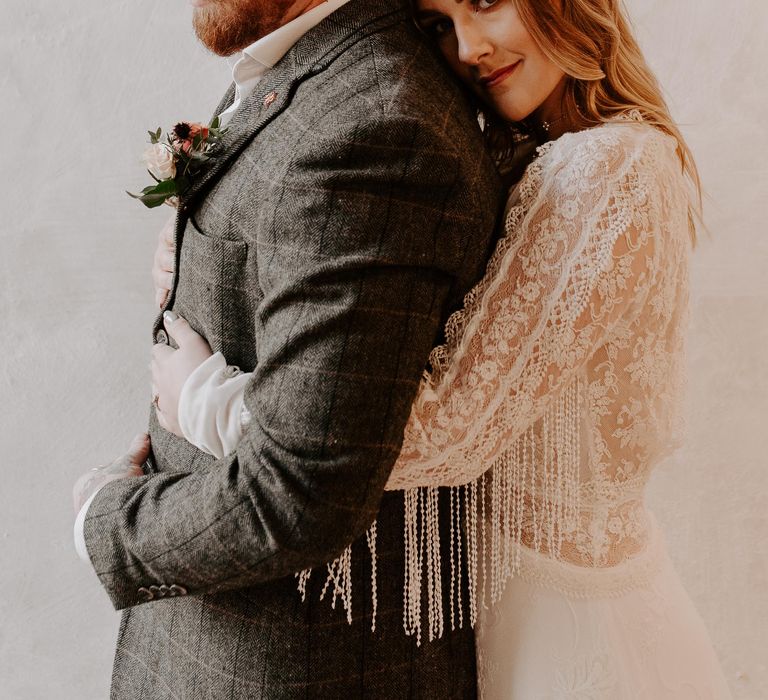 Bride in fringe sleeve wedding dress hugs her groom