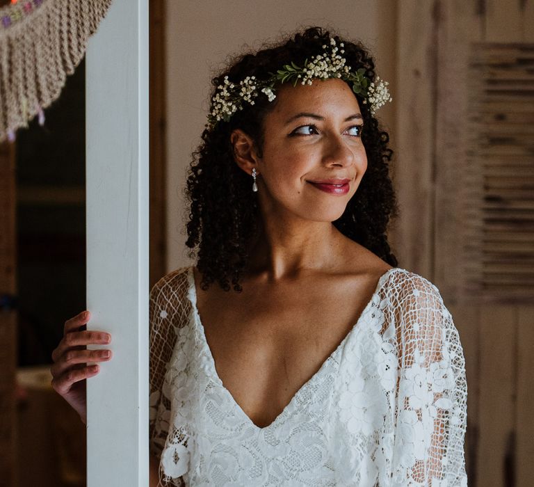 Black bride looks to the side and smiles as she wears her hair naturally and with a simple floral crown