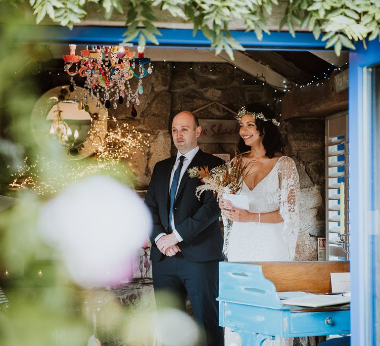 Bride & groom stand within barn on their wedding day during ceremony with rustic vibe