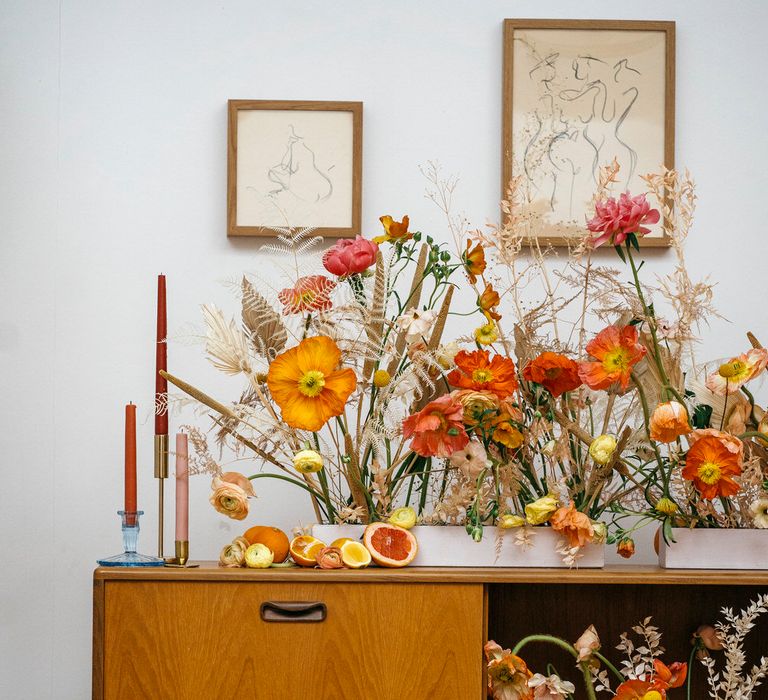 70s wedding decor with fresh poppies and dried flowers, tapered candles and citrus fruits