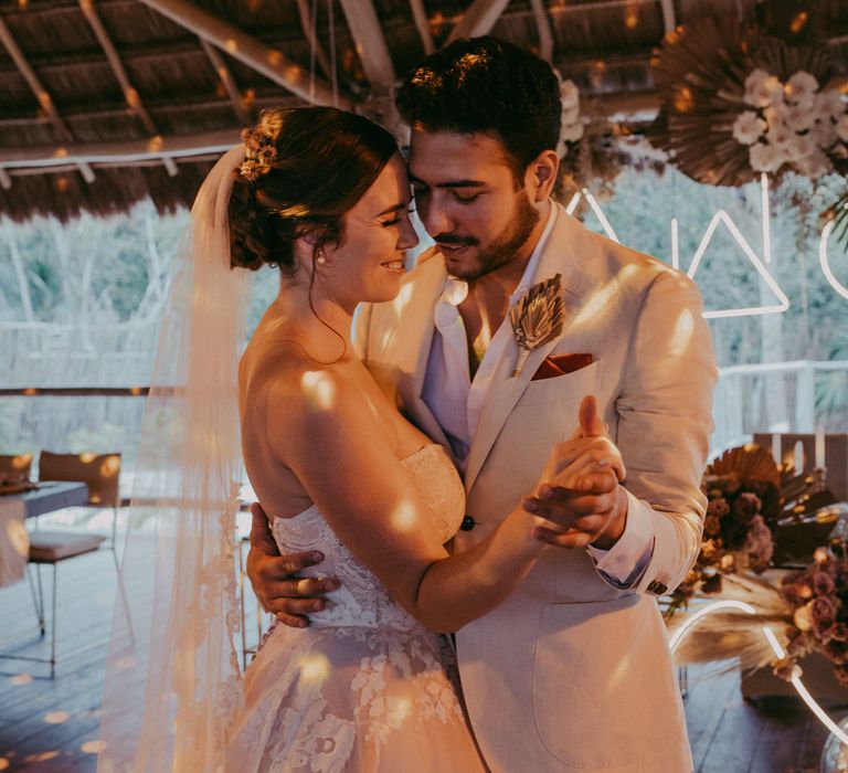 Bride & groom dance with one another on their wedding day as lights shine around them