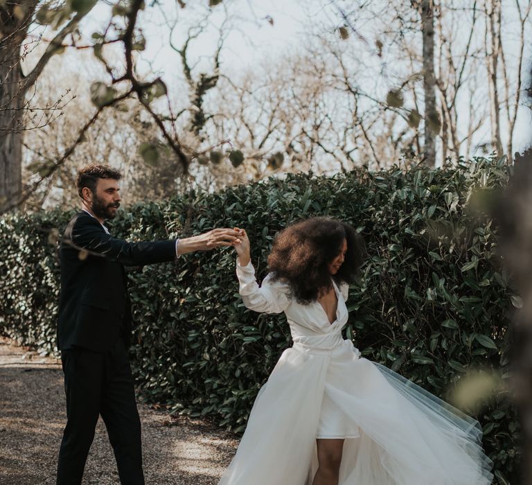 Groom twilling his bride in a high low wedding dress with pencil skirt and tulle overlay 