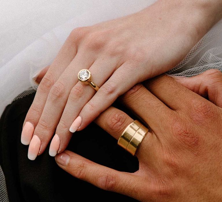 Bride and groom holding hands showing off their wedding rings