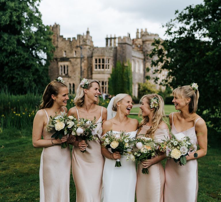 Bridal party portrait in front of the castle wedding venue in satin slip bridesmaid dresses 