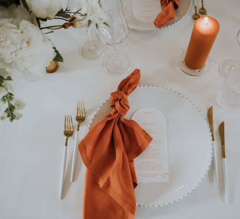 Place setting with orange napkin and on the day stationery menu card 