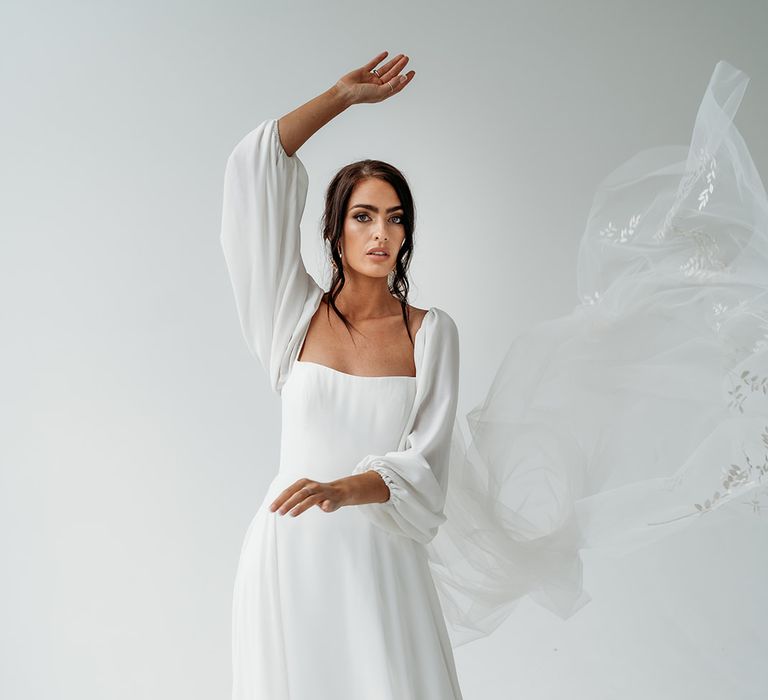 Ethereal wedding dress with floaty long sleeves wearing a cathedral length veil with embroidered laurel design on the train 