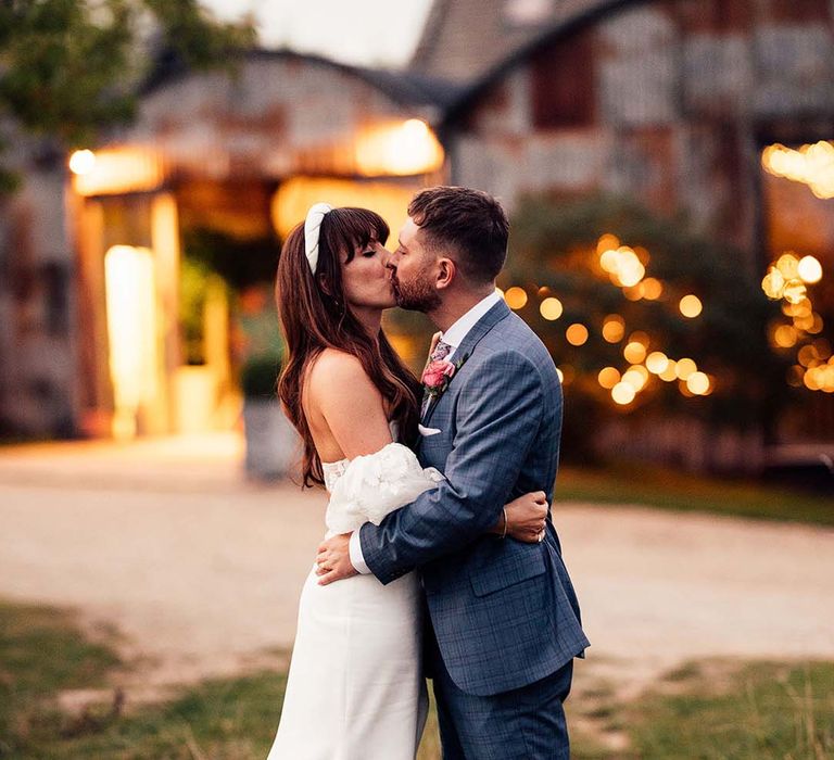 Bride & groom kiss on their wedding day as the sun begins to set at the Stone Barn Cotswolds 