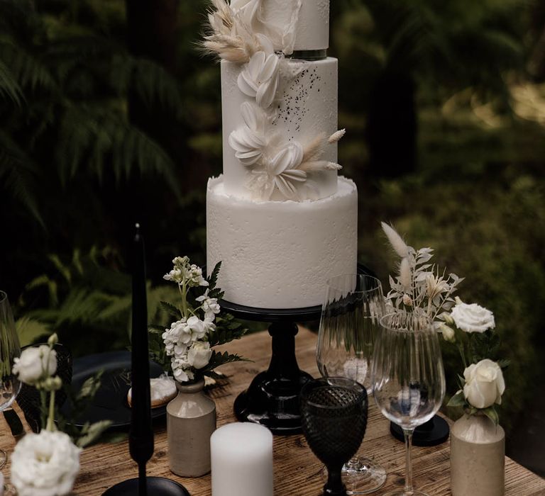 Four tier buttercream wedding cake on a black cake stand with bunny ears and macaroon decor 