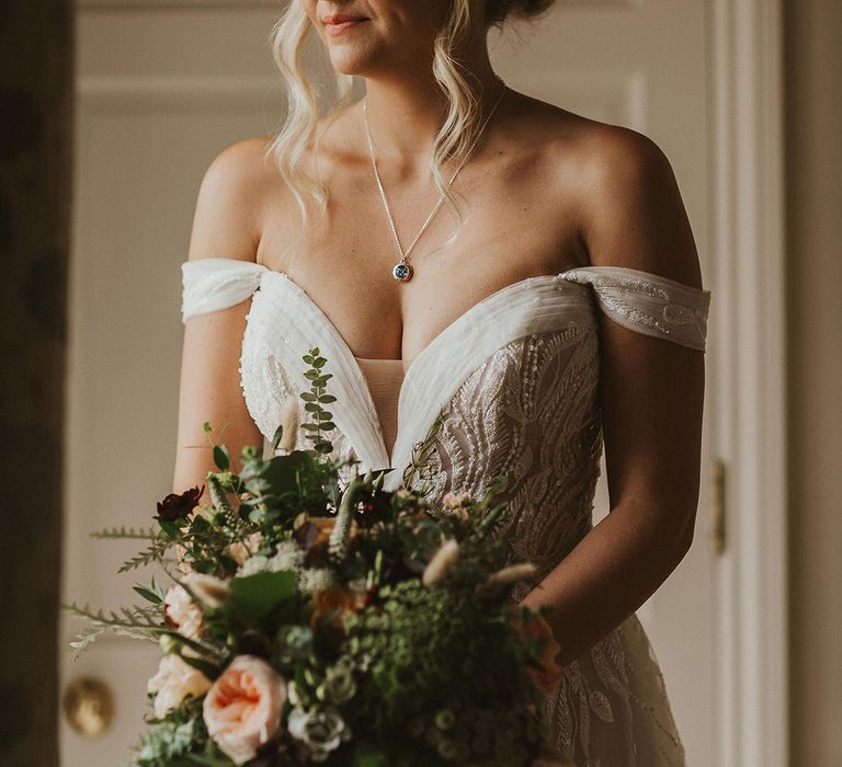 Bride in off the shoulder wedding dress clutches flower bouquet