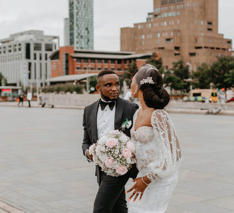 Bride & groom walk through Liverpool as bride holds her floral bouquet