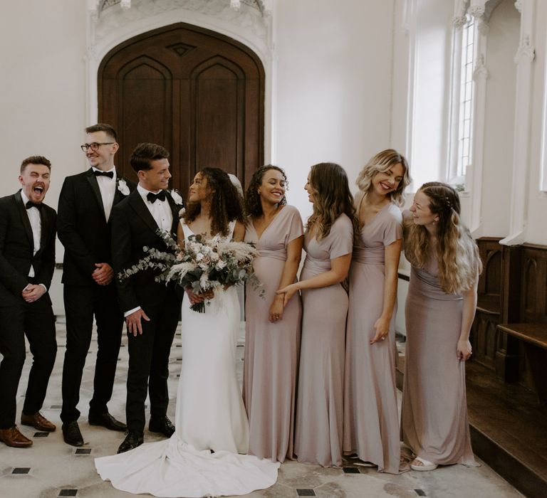 Bride & groom stand with their groomsmen and bridesmaids