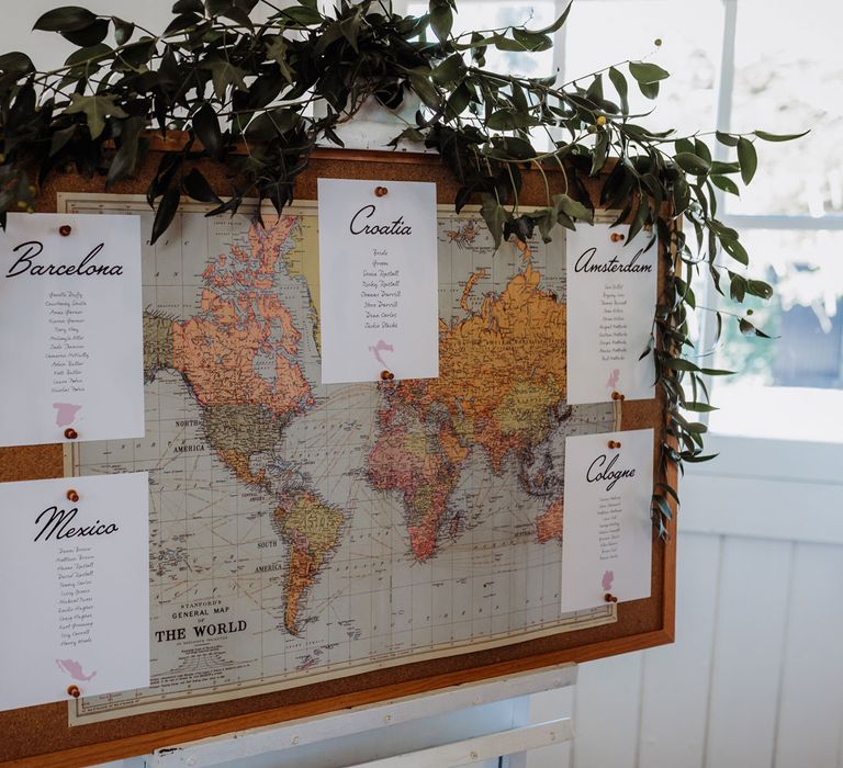 World map wedding table plan with foliage garland on corkboard 