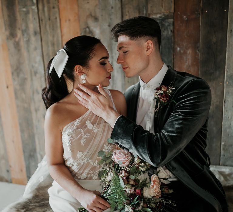 Bride and groom look lovingly at one another in front of wooden rustic backdrop