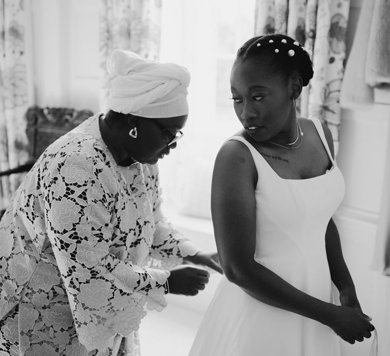 Black African Mother of the bride doing up her daughters Essense of Australia wedding dress 