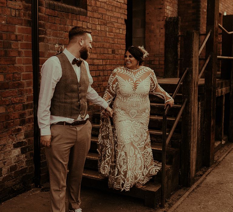 Intimate bride and groom portrait with groom in a tweed waistcoat and wool trousers holding hands with her bride in a Rue de Seine wedding dress 