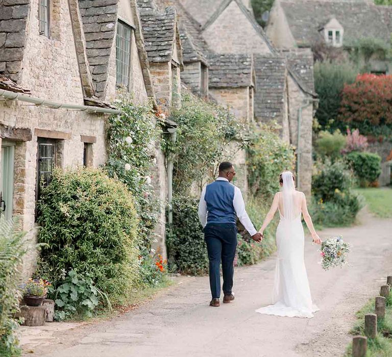 Bride & groom walk hand in hand through the Cotswolds 