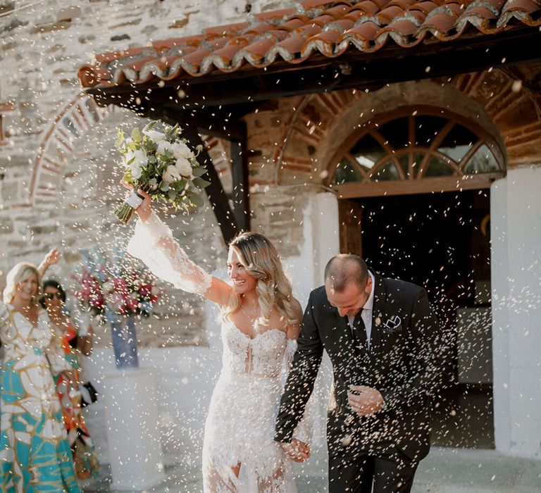 Bride & groom walk through confetti on their wedding day outdoors in Greece