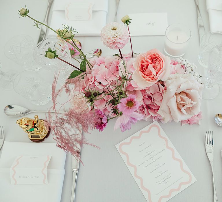 Pink flower arrangements for wedding reception with maneki-neko decor and pink and white wedding stationery 