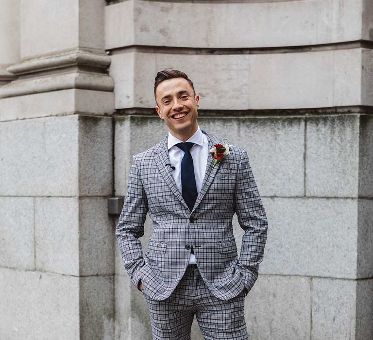 Groom wears grey striped suit complete with tie and floral buttonhole 