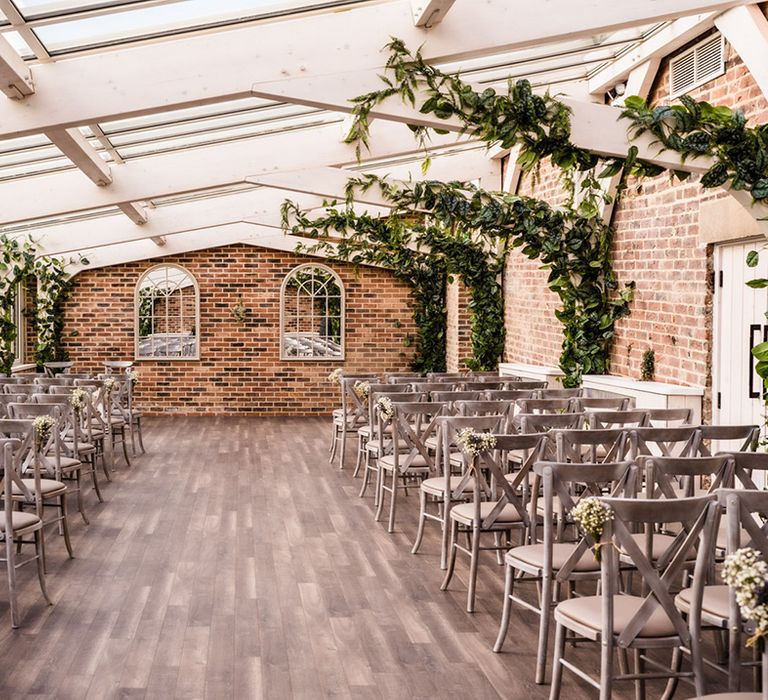 Wedding ceremony room at Foxtail Barns wedding venue with grey chairs and decorative greenery