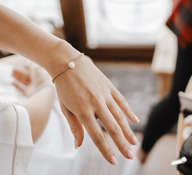 Bride's classic French tip wedding nails with gold chain bracelet and pearl jewellery 