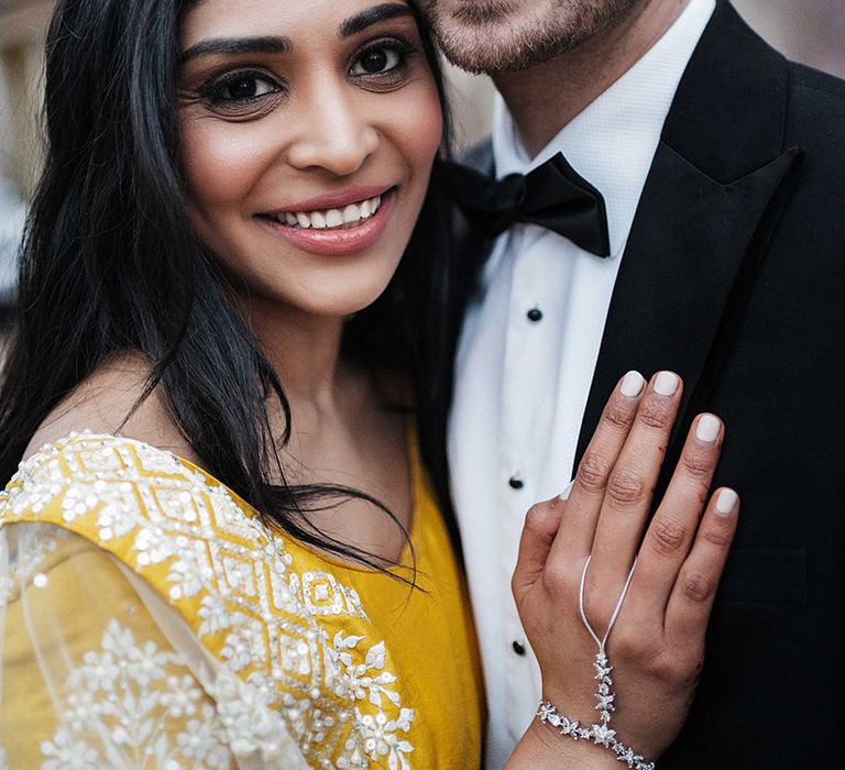 Groom in black tie with bride in yellow Lengha and silver jewellery 