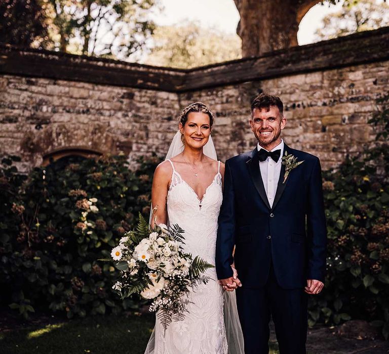 Bride and groom pose together for their couple portraits holding hands 