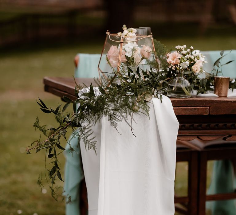 Wedding decor including drapes, foliage, candles and wooden stumps and hurricane vases filled with pine cones 