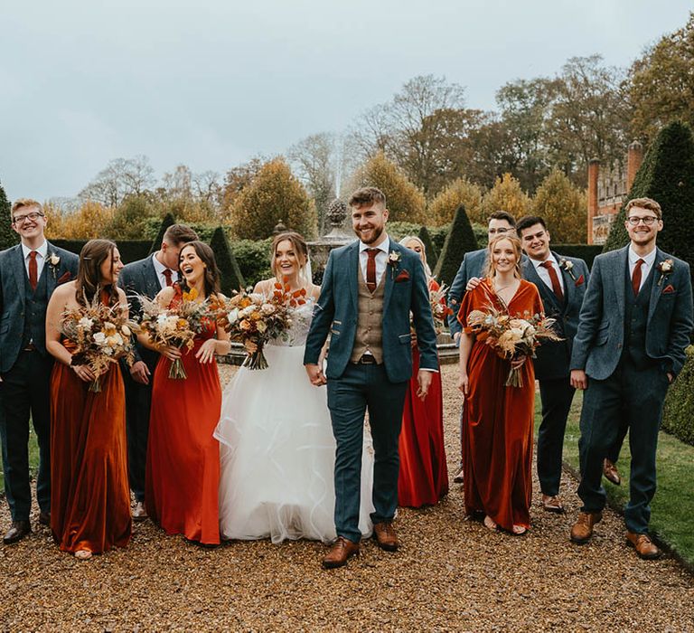 Bride in Blush by Hayley Paige wedding dress, bridesmaids in orange dresses and groom and groomsmen in blue suits, brown waistcoats and burnt orange ties 