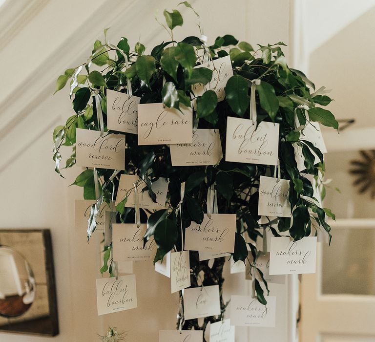 Green plant wedding table plan idea with small white seating chart cards 