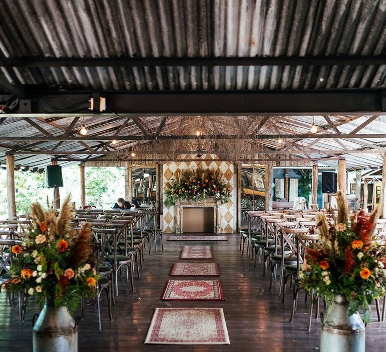 The Dreys wedding venue ceremony room decorated with pampas grass and astilbe with Persian rugs and throws 