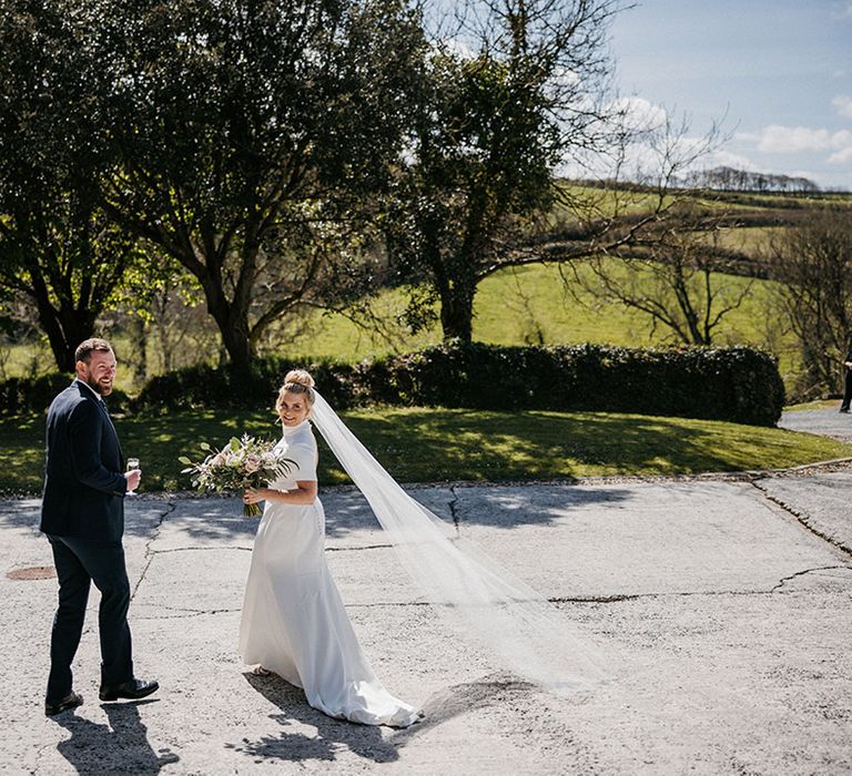 Bride wearing a Jesus Prior wedding dress and veil with groom in blue suit for their Launcells Barton wedding 