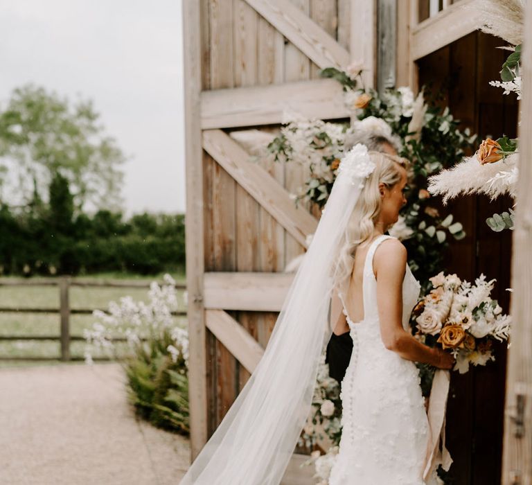 Bride walking in a 3D floral appliqué wedding dress with a floral veil 