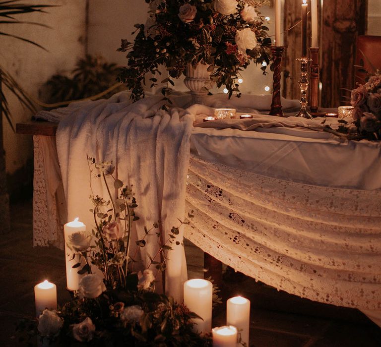 White winter wedding tablescape with pillar and taper candles and pink rose flower arrangements 