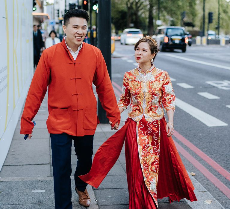 Bride & groom wear traditional Chinese attire as they walk down the street with one another on their wedding day