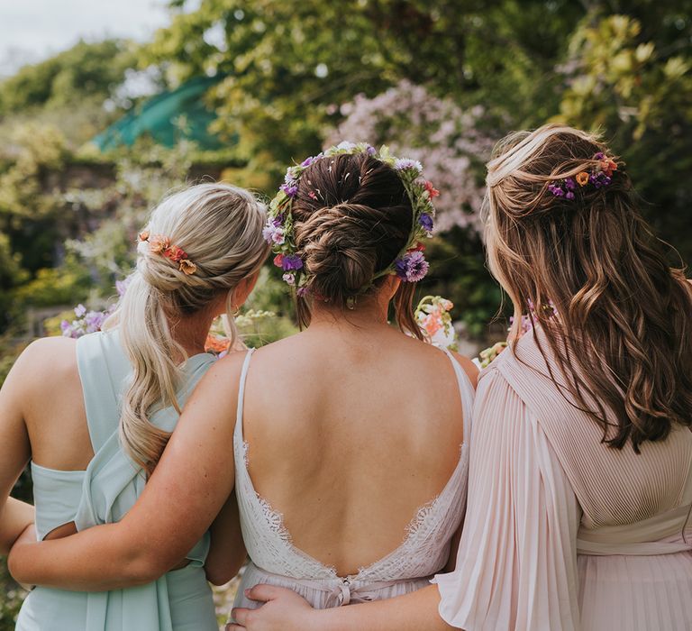 Bride and her bridesmaids wear colourful florals in their hair for outdoor wedding 