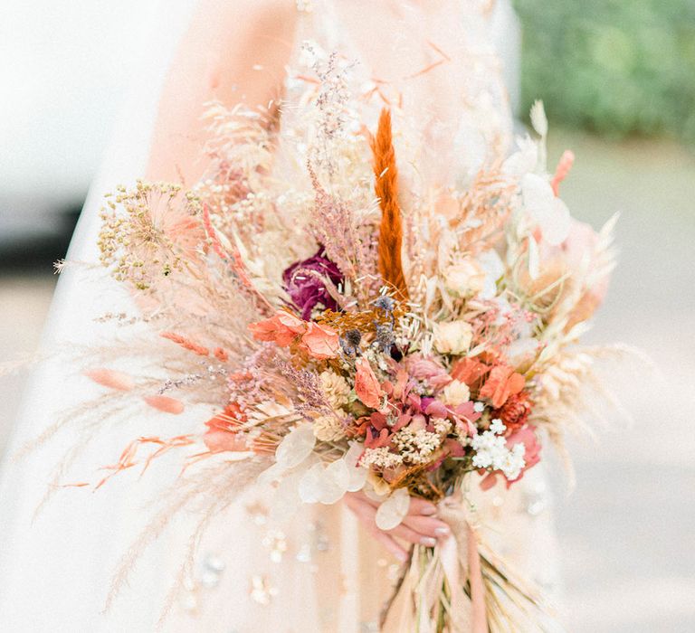 Blonde bride carries Autumnal dried floral bouquet on the morning of her wedding day