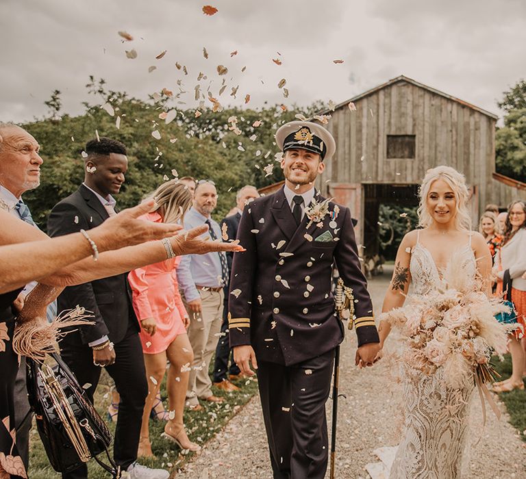 The bride and groom exit from their ceremony to their wedding guests throwing confetti 